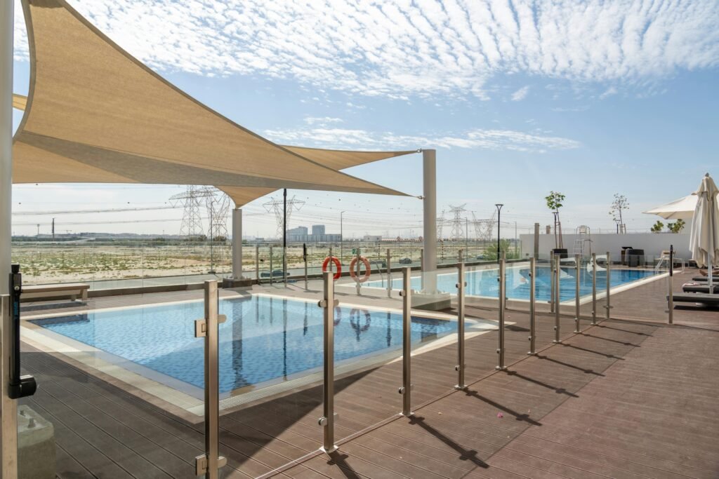 Sunny day at a contemporary outdoor pool with Dubai skyline in the backdrop. Ideal for relaxation.